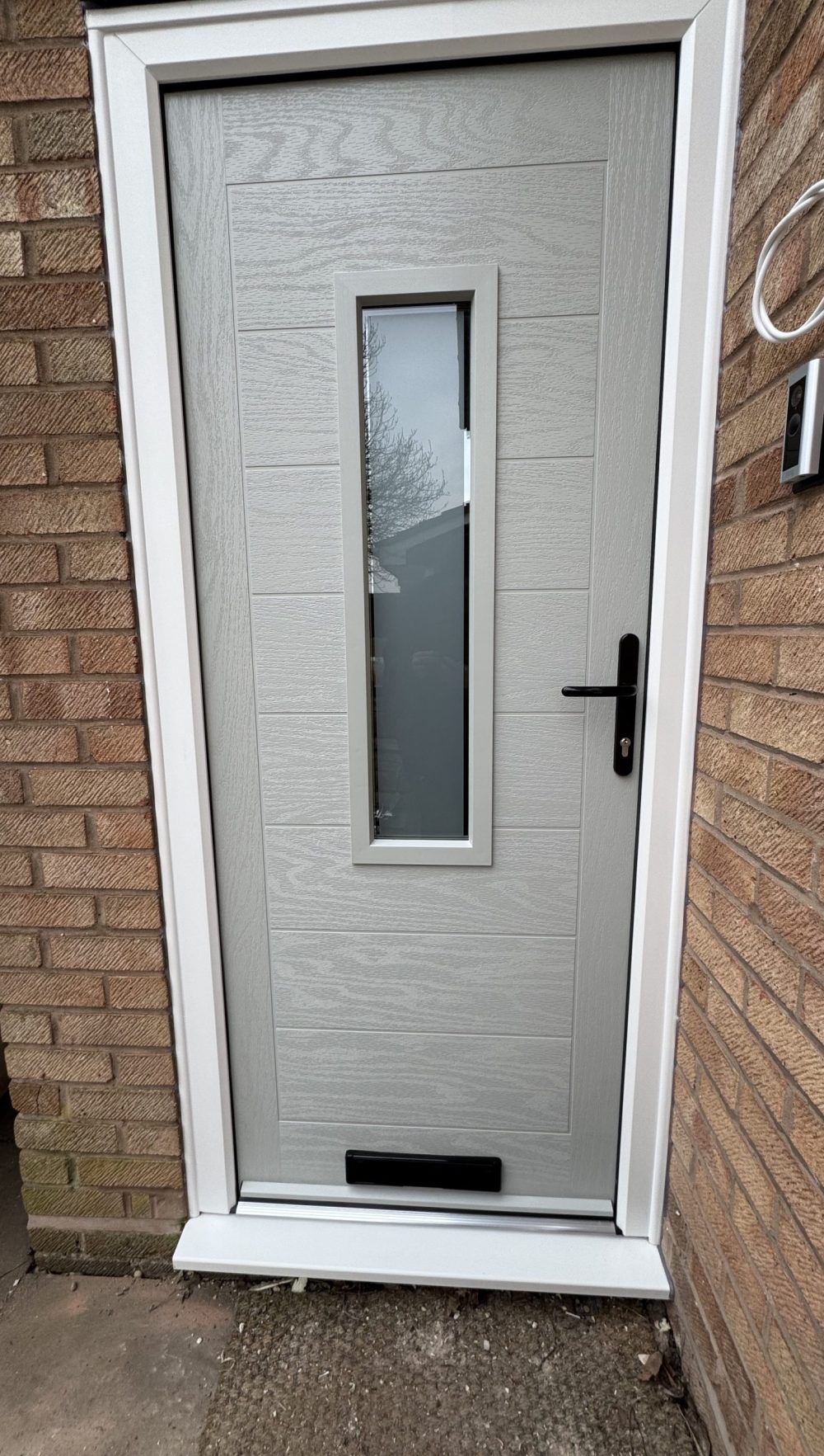 Light grey composite front door with vertical glazed panel installed by uPVC Houselift in Perton
